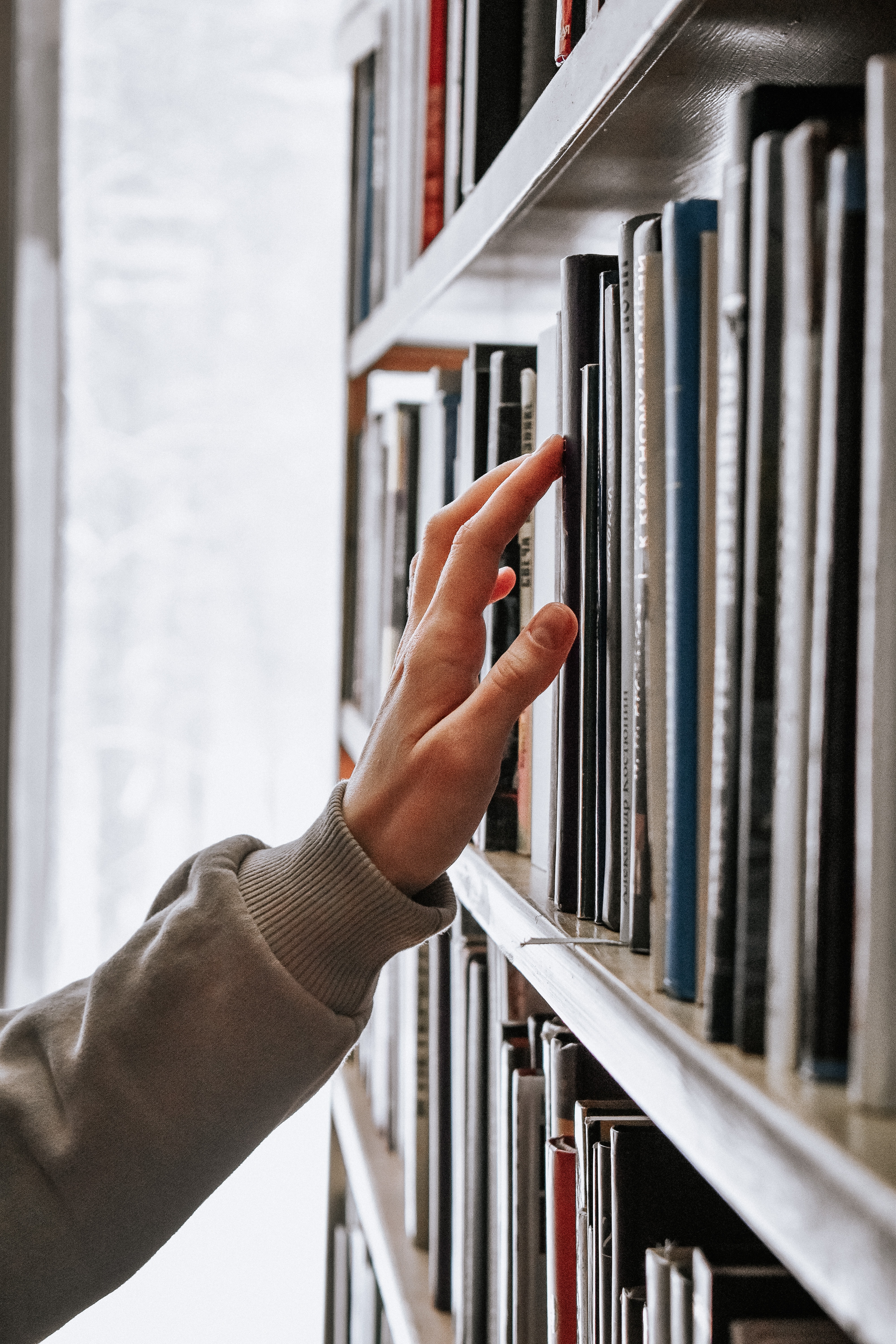 main qui cherche un livre dans une bibliothèque